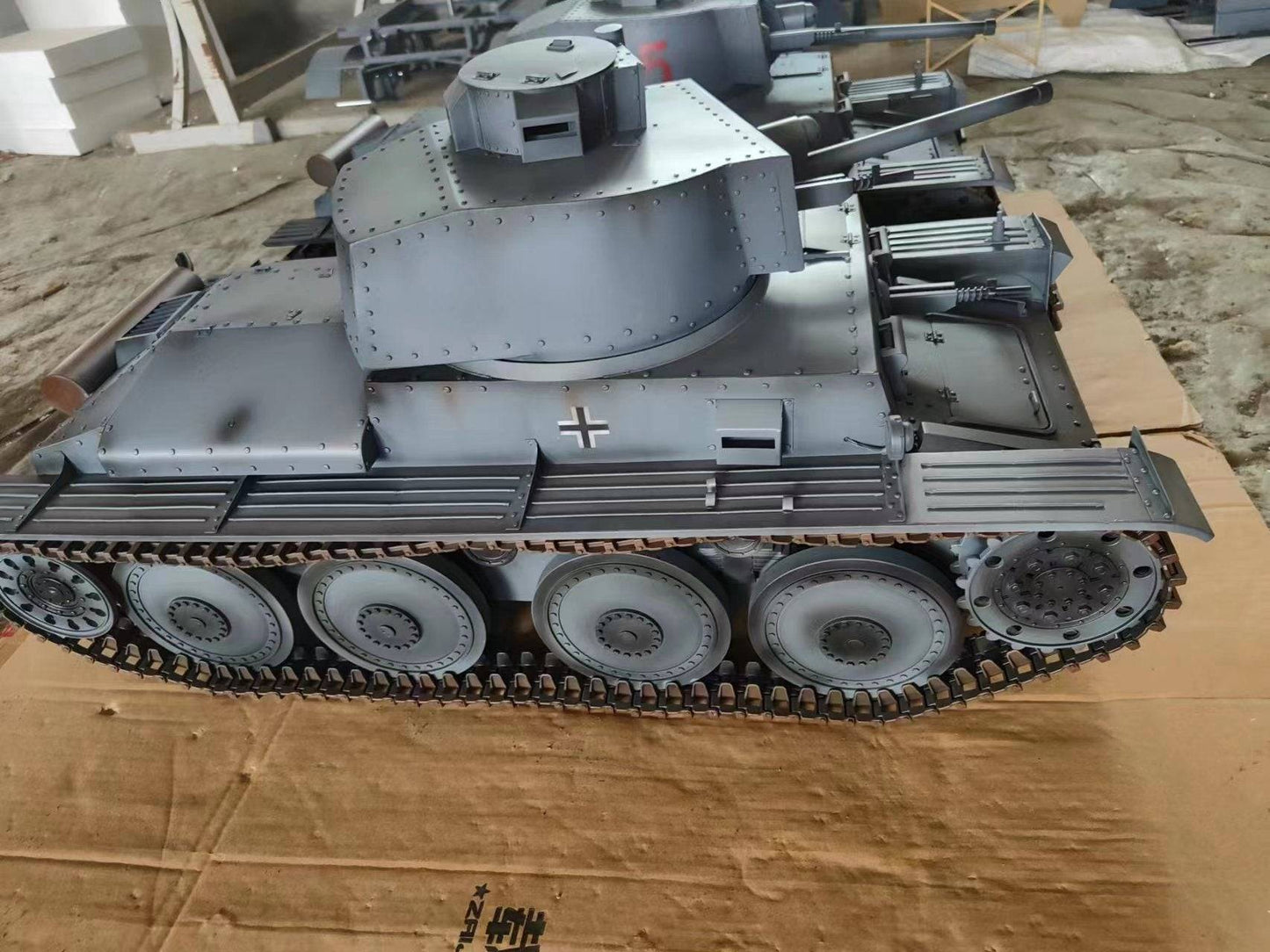 A detailed eaxtoys 1/6 scale Panzerkampfwagen 38(t) tank model with visible tracks, turret, and gun barrel on a brown cardboard surface, featuring a military insignia on the side to captivate WWII German tank model enthusiasts.