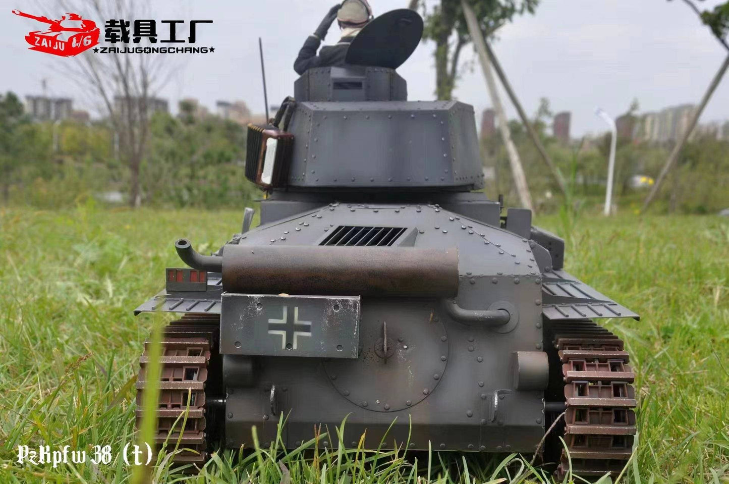 The 1/6 scale eaxtoys Panzerkampfwagen 38(t) model, ideal for military enthusiasts, features a grey riveted body with caterpillar tracks and a top cannon. A German cross insignia stands out amid grass, while trees and buildings blur in the background.