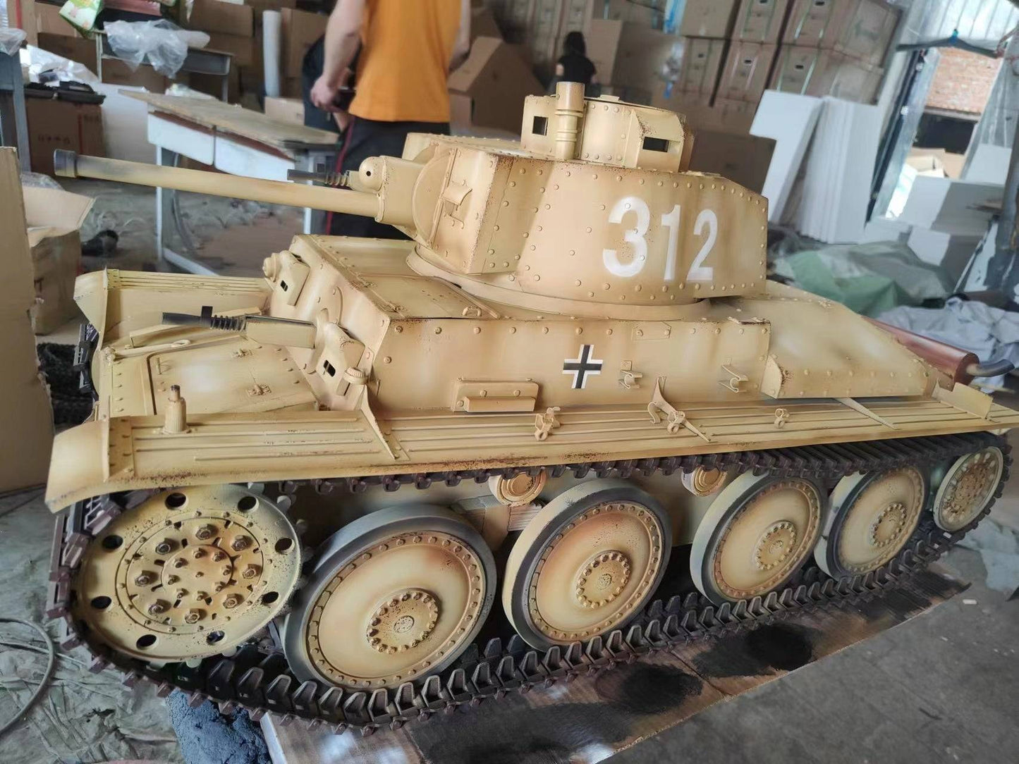 The eaxtoys 1/6 scale Panzerkampfwagen 38(t) features the number 312 and a German cross on its turret. Displayed indoors with various items around, its perfect for military model enthusiasts who appreciate detailed WWII historical pieces.