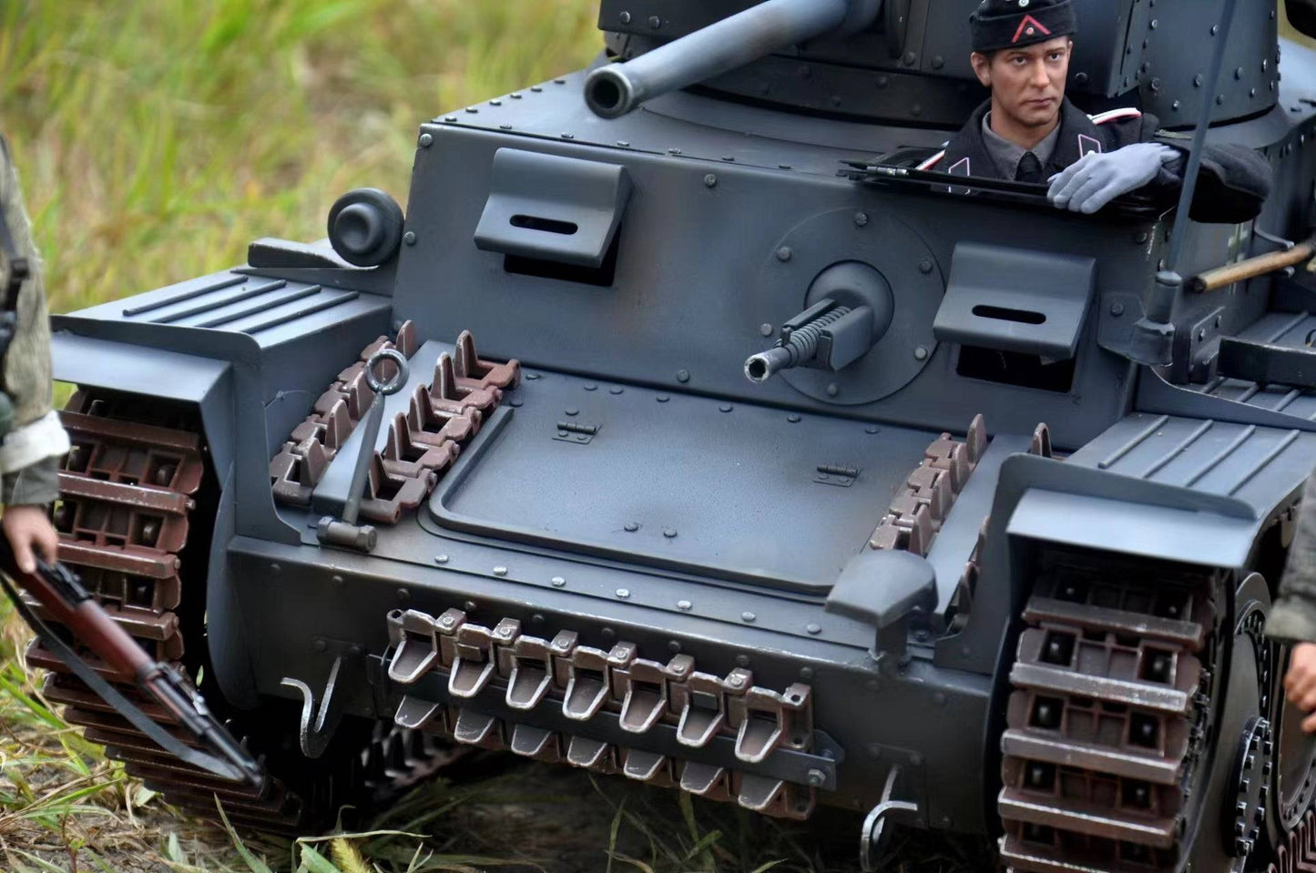 The eaxtoys 1/6 scale Panzerkampfwagen 38(t) model tank features a detailed exterior with a uniformed figure at the top hatch. Positioned on grassy terrain, it showcases intricate tracks and weaponry, perfect for military model enthusiasts.