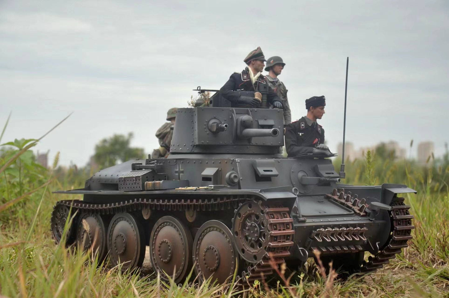 The eaxtoys 1/6 scale Panzerkampfwagen 38(t) model captivates on the grass, featuring four intricately detailed soldier figures in WWII uniforms. Ideal for military model enthusiasts, the tank showcases dark hues with visible tracks and turrets beneath an overcast sky for realism.