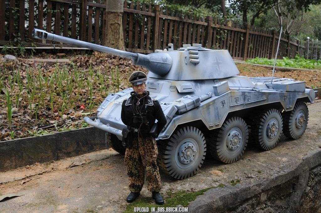 Miniature officer standing in front of the EAXTOYS 1/6 scale WWII German Sd.Kfz.234/2 Puma model on a paved road.
