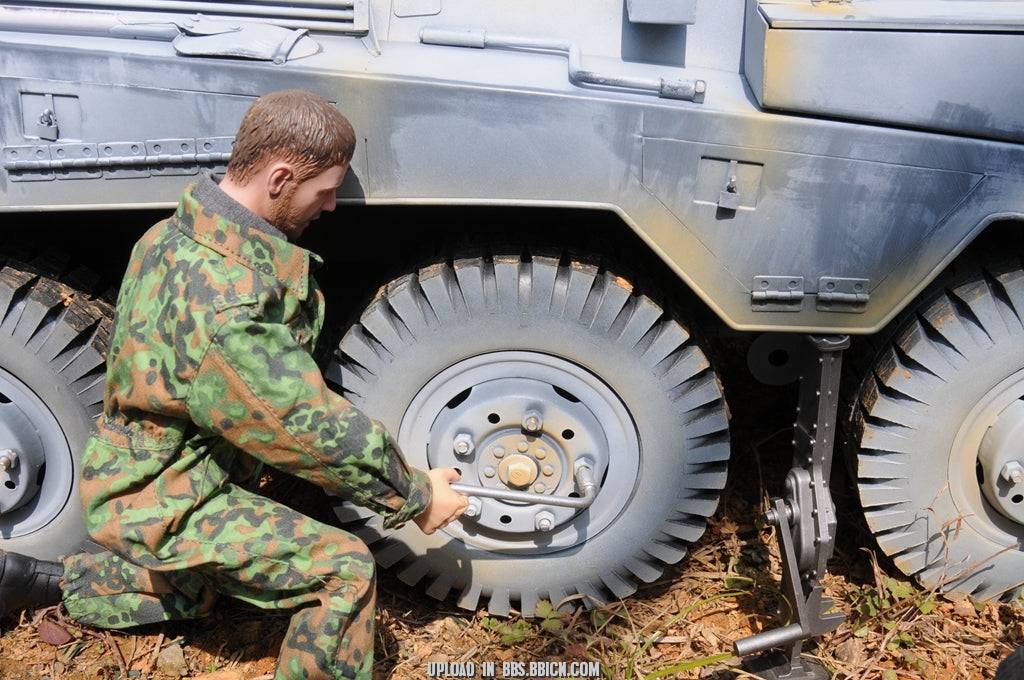 Miniature soldier in camouflage uniform tightening a wheel bolt on the EAXTOYS 1/6 scale WWII German Sd.Kfz.234/2 Puma model.