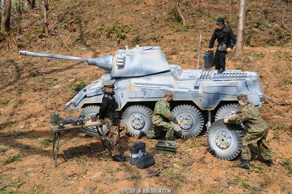 Diorama scene with miniature soldiers repairing the EAXTOYS 1/6 scale WWII German Sd.Kfz.234/2 Puma model in a realistic outdoor setting.