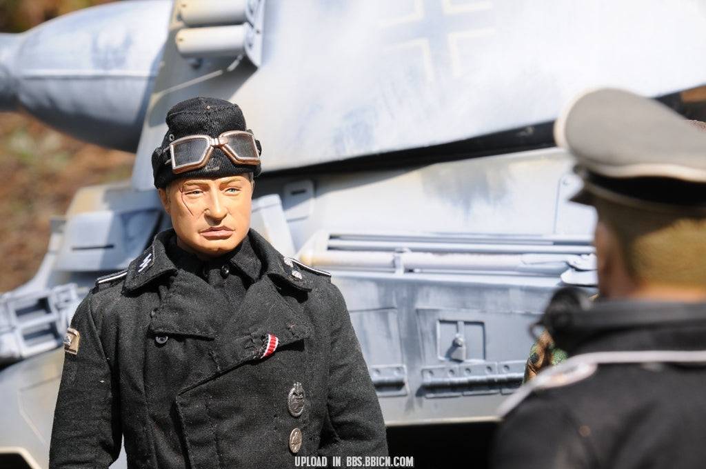 Close-up of a miniature soldier in black uniform standing beside the EAXTOYS 1/6 scale WWII German Sd.Kfz.234/2 Puma model.