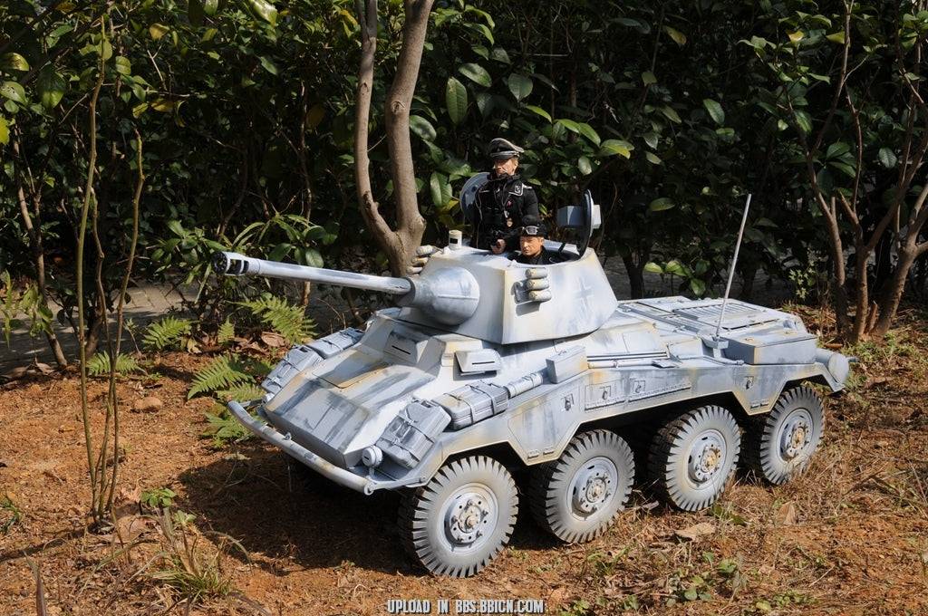 Miniature soldier standing beside the EAXTOYS 1/6 scale WWII German Sd.Kfz.234/2 Puma model in a forest setting.